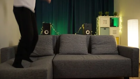 Man in isolation is crazy, jumps on the couch Stock Footage 129384424
