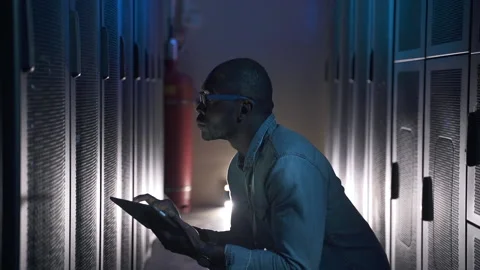 Man IT engineer checking equipment and working with tablet while sitting in big Stock Footage 163814193