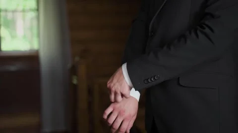 A man in a jacket adjusts the sleeves of his shirt Stockbeeldmateriaal 329093320