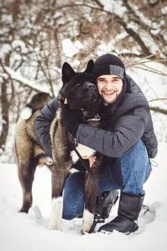 A man in a jacket and a knitted hat walks with an American Akita dog Stock Photos