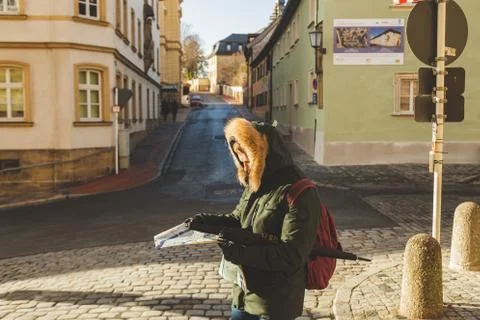 A man in a jacket checking map while walking in the downtown Stock Photos