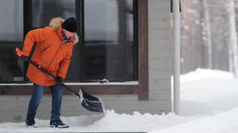 Man in jacket cleans track from snow with shovel in yard Stock Footage 138871104