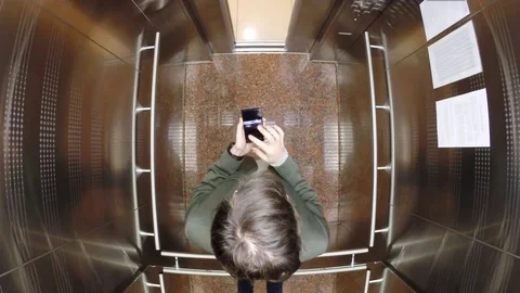 Man in jacket close doors and touch smartphone in hands in elevator cabin. 스톡 동영상 83110849