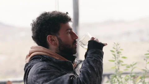 Man in Jacket Enjoys Refreshing Drink at Mountain View Restaurant Video stock 335986788