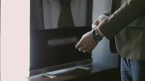Man in a jacket fastens his watch on his arm Stock Footage 79610461
