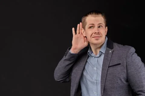 A man in a jacket hears important information on a black background. Stock Photos