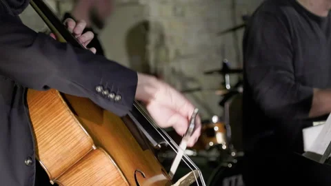 A man in a jacket playing cello with a band. Stock Footage 273809670