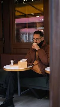 Man in a jacket sits on an open cafe terrace on an autumn day drinking matcha  Stock Photos