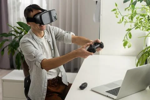 A man in a jacket is studying a new profession. A VR programmer plays a virtual Stock-Fotos