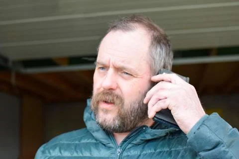 A man in a jacket talking on a mobile phone. Stock Photos