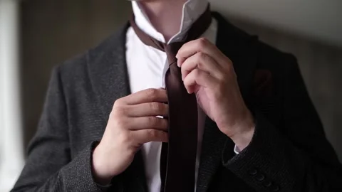A man in a jacket tying a tie Stock Footage 137227086