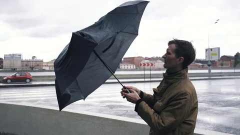 Man in jacket with umbrella. The gust of wind pulls umbrella out of hand of man Stock Footage