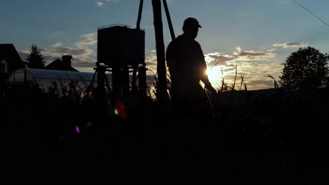 A man in a jacket is walking on a farm plot. the sun hits the camera with a ray Stock Footage 161033621
