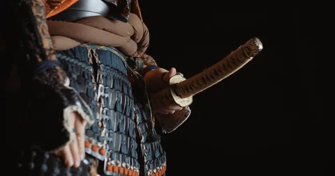 A man in japanese samurai armour is taking a sword out of his scabbaders Stock Footage