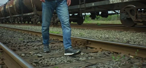 Man in jeans walking on railways near oil tank train Stock Footage 201141653