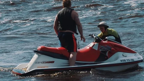 Man on jet ski rides around surfer boy and his coach who floats in water 動画素材 71812036