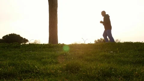 A man jog in a park, contrast backlight silhouette at sunset Stock Footage 104047963