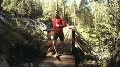 Man jogging in the alpine forest through the wood bridge. Stock Footage 53845292