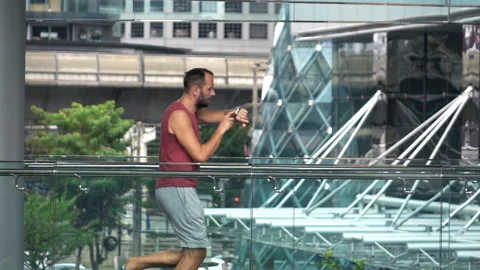 Man jogging and checking time on smartwatch in city, super slow motion 240fps Stock Footage 134640206