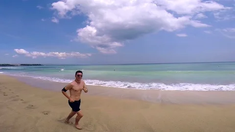 Man jogging and waving on beautiful tropical beach. Stock Footage 80245249