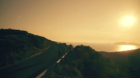 Man jogging on asphalt road on a mountain with view of the ocean at sunset Stock-Footage 77145445