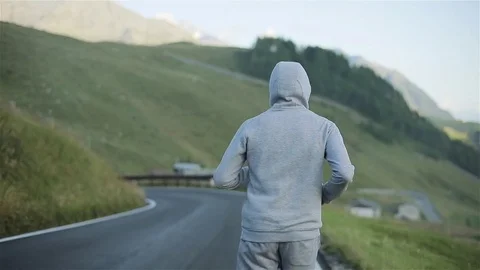 Man jogging back on countryside mountain road in nature close up slow motion Stock Footage 79975155