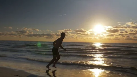 Man jogging barefoot on the beach at sunrise Stock Footage