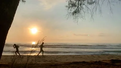Man jogging on beach with sunrise background Stock Footage 147939560