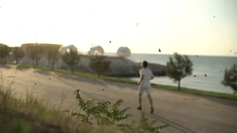 A man jogging, butterflies fly by Stock Footage 129107501