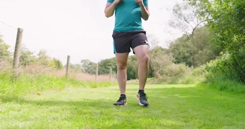 Man jogging on grassy path in park, enjoying outdoor exercise Stock Footage 346295976