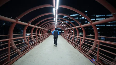 A man jogging on a metal red colored skywalk during early morning hours Stock Footage 129530106