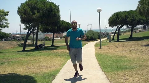 Man jogging on park and checking time on phone and watch, super slow motion  Stock Footage 76430990