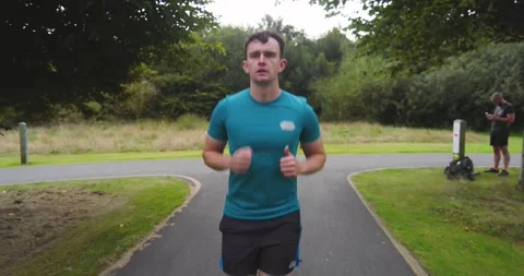 Man jogging on park path, wearing athletic gear, enjoying outdoor exercise Stock Footage 346295971