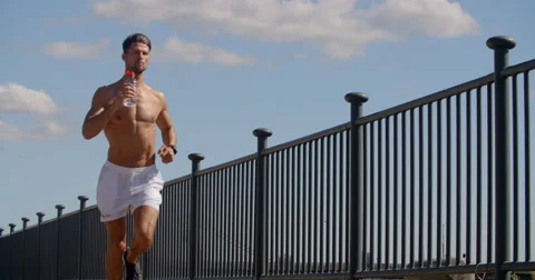 Man Jogging Takes sip of liquid. Vídeo Stock 68042770