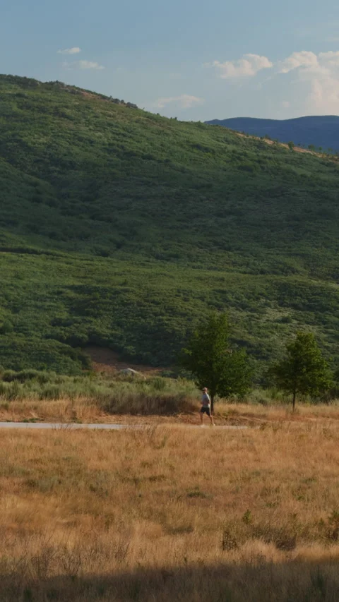 Man Jogging on Trail with Massive Mountain Background Stock Footage 345607071