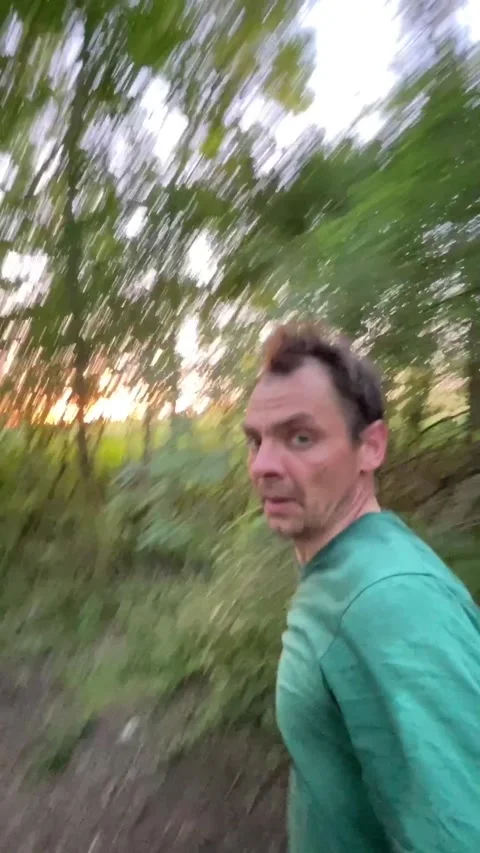 Man jogging on wooded trail at sunset in profile with red cloth in hand, with Vidéo 344583698