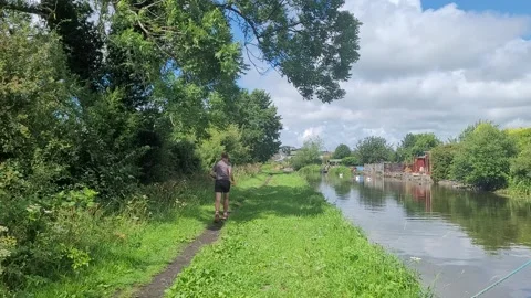Man jogs away from camera, canal towpath, UK Stock Footage 245935682