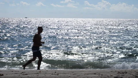 Man Jogs Past Ocean Water Sparkles Stock Footage 208954994