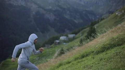 Man jogs runs up mountain hill face close up slow motion. Hooded runner jogger Stock Footage 79974785