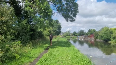 Man jogs towards camera, canal towpath, UK Stock Footage 245935672