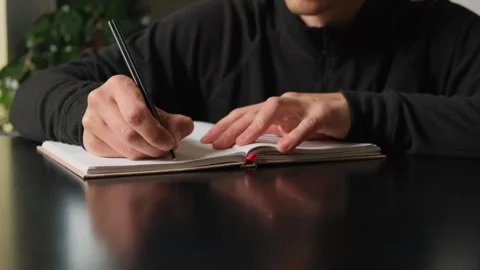 Man journaling his thoughts in a notebook at home, reflecting on personal Stock Footage 316069631