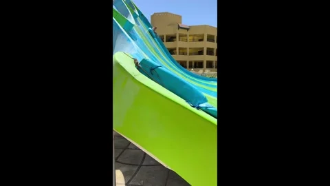 Man joyfully slides down a water slide at an amusement park, laughing and relish Stock Footage 334184916