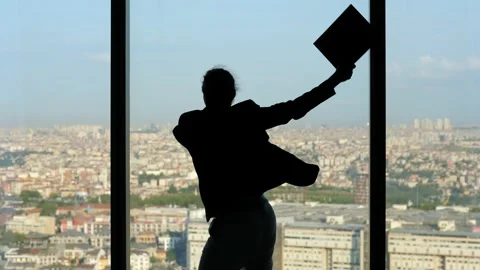 Man joyously celebrates, dancing with exuberance, silhouetted against window Stock Footage 259466409