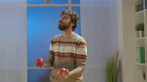 Man juggling with apples at home Stock Footage 128779995