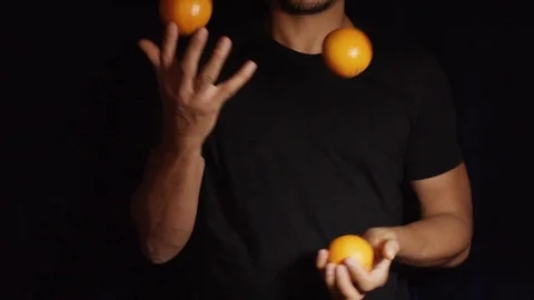 Man juggling three oranges, in slow motion Stock Footage 83334965
