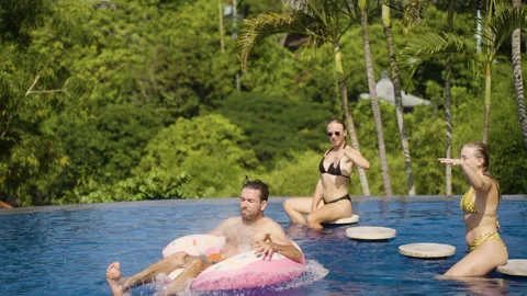 Man jump on inflatable ring in pool on luxury private villa on pool party Stock Footage 259159973