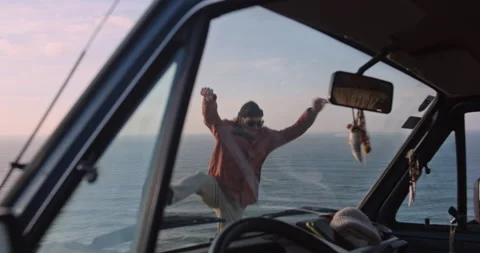 Man Jumping in Background Seen Through Van Windows with Ocean at Sunset Stock Footage 238953073