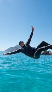 Man jumping backwards from a boat into tropical blue ocean Stock Photos