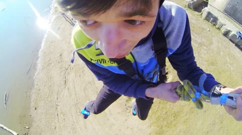 Man jumping from the bridge facing forward clutching the rope Stock Footage 52430444