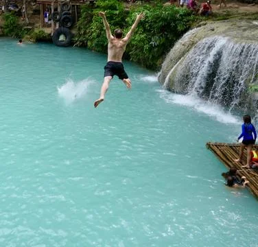Man jumping from cliff into natural pool with waterfall, Siquijor, Philippines Stock Photos